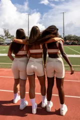 Top deportivo azul con contorno y tirantes blancos, banda inferior blanca con logo en rojo y borde inferior rojo.