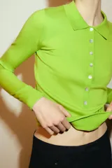 Jersey de punto fino confeccionado en lana, con cuello polo, cierre frontal de botones y manga larga.