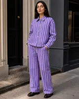 Sobrecamisa de corte oversize a rayas violetas y blancas, con cuello clásico, cierre frontal de botones y bolsillos frontales.