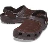 Zueco Crocs Yukon Vista II color gris oscuro, con parte superior de material sintético que simula cuero, costuras decorativas en el empeine y orificios de ventilación frontales. Posee correa ajustable en el talón de color gris claro.