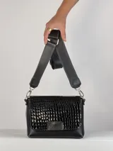 Bandolera negra de cuero con textura tipo cocodrilo en la solapa frontal, correa larga regulable y herrajes plateados.