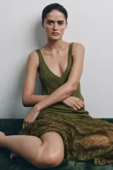 Vestido midi de punto acanalado color verde oliva, con escote en V y tirantes anchos. La parte superior presenta un diseño de tejido rib, mientras que la parte inferior está terminada con una aplicación de encaje transparente al tono.