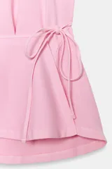 Top halter de mezcla de algodón en color rosado, con cuello halter ajustable mediante lazada, espalda descubierta y detalle de fajín cruzado con lazo en la cintura.
