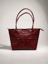 Cartera tipo tote bag de cuero vacuno color marrón oscuro, de diseño estructurado con asas largas para llevar al hombro y cierre superior. Presenta detalles de costuras decorativas y pespuntes en el frente.