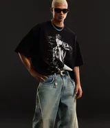 Pantalón de jean negro estilo super baggy, con diseño holgado, tiro alto y detalles de costuras deshilachadas a lo largo de las piernas.