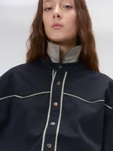 Camisa de estilo western confeccionada en algodón grueso color negro. Presenta detalles de costuras decorativas en tonos claros en el pecho y a lo largo de la cartera de botones. Posee cuello clásico, cierre frontal con botones y un calce holgado.