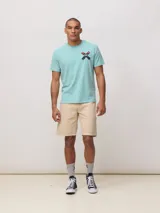Remera de algodón orgánico color blanco, con corte regular fit y detalle de bordado en forma de X con diseño geométrico multicolor en el pecho.