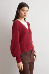 Cardigan de punto acanalado color bordó, con escote en V, cierre frontal de botones y mangas largas abullonadas con puños ajustados.