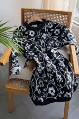 Suéter largo de punto con diseño floral en tonos blanco y azul, de corte holgado, cuello redondo y mangas largas con puños acanalados. Puede utilizarse como vestido tejido.