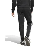 Pantalón deportivo Adidas modelo Tiro Esencial, color negro con las icónicas tres tiras blancas laterales y logo de la marca bordado en la pierna. Cuenta con cintura elástica y puños ajustados en los tobillos.