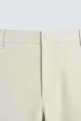 Pantalón de corte slim fit confeccionado en tejido elástico, con cintura elástica, cierre frontal con cremallera y botón, bolsillos laterales y bolsillos traseros de vivo.