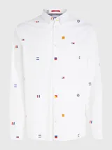 Camisa blanca de popelina de puro algodón con estampado de banderas náuticas y logos de Tommy Jeans bordados. Corte clásico, cuello abotonado, puños con botón y bajo redondeado.