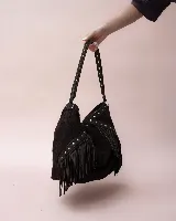 Cartera tipo hobo de gamuza color marrón oscuro, con diseño boho que incluye flecos laterales y detalles de tachas metálicas en el asa y el cuerpo. Cuenta con un compartimento principal amplio y forro interior.