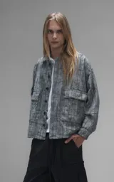 Campera de denim rígido con diseño de trama texturizada en tonos grises y negros. Presenta cuello camisero, cierre frontal con botones, mangas largas y dos bolsillos frontales con solapa.