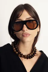 Lentes de sol con armazón de policarbonato color marrón traslúcido y diseño envolvente de una sola pieza.