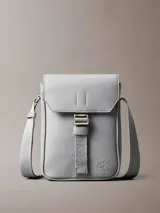 Cartera reporter Calvin Klein color gris, de diseño compacto con solapa frontal y correa ajustable para el hombro. Cuenta con detalles de marca grabados y correa central ajustable.