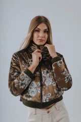 Campera bomber color marrón con estampado floral en tonos blancos y grises, confeccionada en tejido satinado con elástico verde en la cintura.