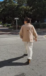 Buzo color beige con cuello alto y cierre parcial, de corte holgado y mangas largas con puños ajustados.