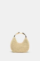 Bolso de mano mini con cuerpo trenzado en color beige y asa rígida metálica dorada. Incluye correa bandolera extraíble y cierre superior de cremallera.