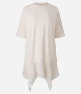 Remera oversized de algodón color beige, de manga corta y cuello redondo, con superposición inferior liviana, bajo asimétrico y aplicación de encaje.