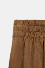 Pantalón de tiro alto color marrón, con cintura elástica ancha y pernera ancha, confeccionado en tejido con efecto ante o gamuza.