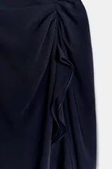 Vestido midi de cuello redondo y manga corta, confeccionado en tejido fluido color azul marino. Presenta un diseño con detalle de drapeado y volado lateral en la parte delantera, con cierre en la espalda mediante abertura y botón.