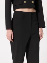 Pantalón negro de vestir, de corte recto y tiro alto, con pinzas en la cintura y ruedo abuchonado.