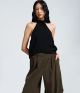 Pantalón sastre de corte barrel, con diseño de piernas anchas y volumen estructurado en los laterales. Presenta pliegues frontales, cintura con elástico en la parte posterior y acabado refinado.