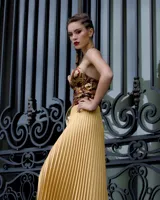 Vestido con falda plisada color dorado y top diseñado en jacquard con estampado paisley en tonos borgoña, ocre y dorado. Se ajusta al cuello con tiras de cadenas doradas.