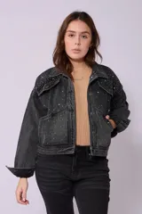 Campera de jean de lavado celeste claro, con diseño clásico de cuello y botones metálicos. Presenta detalles de pequeños brillos o tachas plateadas sobre la tela, especialmente visibles en los bordes de los bolsillos y costuras.