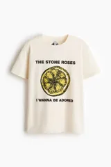 Remera de punto suave de algodón, color beige, con hombros ligeramente caídos y cuello redondo ribeteado acanalado. Cuenta con estampa frontal de la banda The Stone Roses con ilustración de un limón y texto.