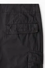 Pantalón cargo de corte holgado en color negro, con múltiples bolsillos laterales con solapa, pliegues en las rodillas y cordones ajustables en el bajo.