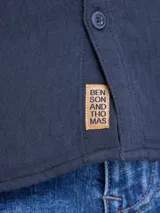Camisa de manga larga en color negro, confeccionada en tejido con textura, con cuello clásico, cierre frontal de botones y un bolsillo en el pecho.