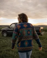 Buzo tejido de punto con diseño geométrico de estilo étnico. Presenta cuello redondo, puños y ruedo acanalados. Confeccionado en una mezcla de lana y fibras sintéticas, con etiqueta de marca en el pecho y en el ruedo.