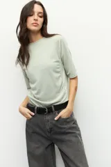 Remera negra de cuello redondo y manga tres cuartos, confeccionada en tela con textura sutil. Presenta fruncidos laterales que aportan caída y movimiento a la prenda.