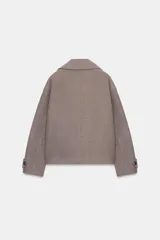 Abrigo corto de paño en color marrón chocolate, con cuello de solapa, cierre frontal cruzado con botones y mangas largas con detalle de trabilla y botón en los puños.