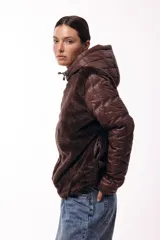 Campera con capucha, cuerpo de pelo sintético y mangas matelaseadas con cierre frontal.