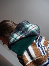 Buzo canguro oversize de paño de lana gris con capucha estampada y cuello de corderito blanco. Cuenta con aberturas laterales en el ruedo y detalles de cuero sintético marrón en el cierre frontal y etiqueta.