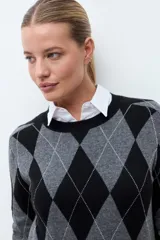 Sweater de punto con diseño de rombos en tonos negro y gris, de cuello redondo y manga larga con puños acanalados.