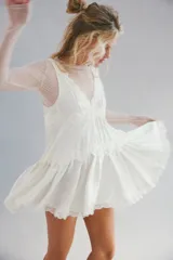 Mini vestido tipo slip de tela satinada negra, con escote en V profundo, diseño en capas con volados y detalles de encaje en los bordes. Corte estilo babydoll, sin mangas y silueta amplia.