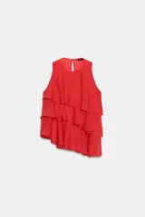 Top rojo sin mangas, con cuello redondo y diseño en capas de volantes con bajo asimétrico. Cuenta con un pequeño cierre de botón en la espalda.
