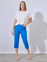 Pantalón capri de gabardina elastizada color celeste, con bolsillos simulados delanteros y bolsillos aplicados traseros. Tiene pretina ancha, corte recto y detalle calado en el ruedo.