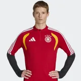 Buzo de entrenamiento de manga larga para hombre, color rojo, con cuello alto y cierre parcial frontal. Presenta detalles en amarillo en los hombros y tres franjas blancas de Adidas en las mangas. Las mangas inferiores son negras con textura. Lleva el escudo de la selección alemana de fútbol con cuatro estrellas en el pecho.