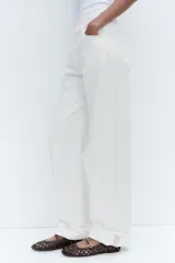 Zapato plano tipo bailarina color marrón oscuro, con capellada trenzada, tira delantera con hebilla metálica y punta redonda.