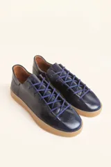 Zapatilla de cuero vacuno color azul marino, con cordones azules y suela de caucho color caramelo.