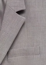 Blazer de corte recto en color beige, con cuello de solapa con muesca, cierre frontal de un botón y bolsillos laterales con solapa. Cuenta con forro interior y mangas largas con puños abotonados.