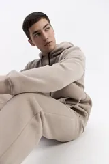 Canguro con capucha y cordones ajustables en color beige, con diseño de calce regular y estampado frontal pequeño.