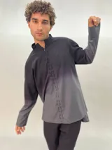 Camisa de lana color gris con cuello mao, corte recto y mangas largas con detalle texturizado. Presenta cierre invisible en el escote superior y tajos laterales.