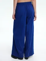 Pantalón de corte holgado y pierna ancha, confeccionado en pana color marrón. Presenta cintura elástica con cordón ajustable y diseño de tiro medio.