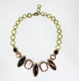 Collar de bronce con piedras naturales engarzadas. Presenta piedras rectangulares blancas nacaradas y piedras ovaladas negras, todas con bordes dorados texturizados.